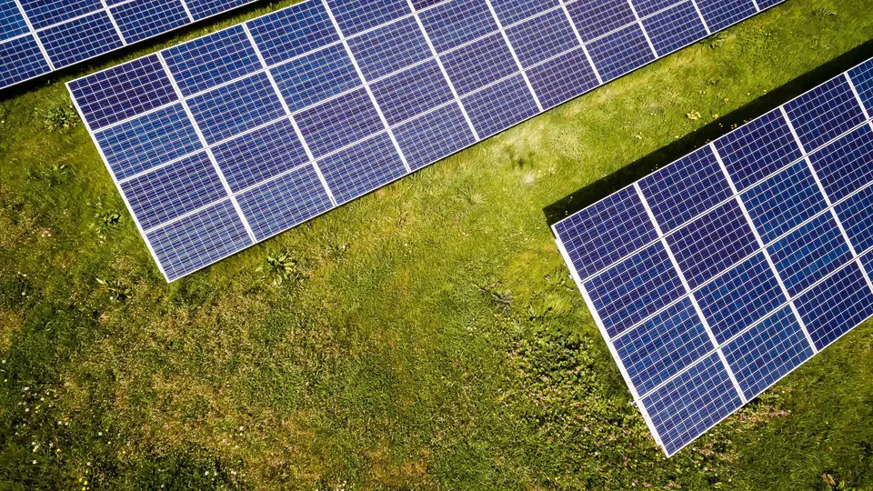 Luftbild von Photovoltaik-Modulreihen auf einer Grünfläche
